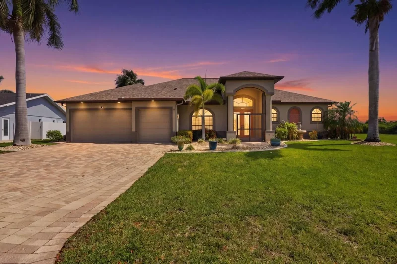 House exterior with a driveway, lawn and palm trees
