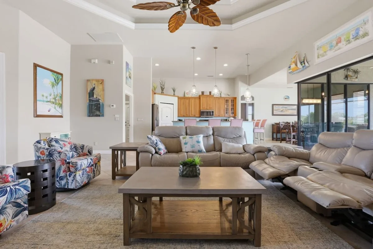 Cape Coral villa living room with sectional seating, a ceiling fan and sliding doors to the pool area