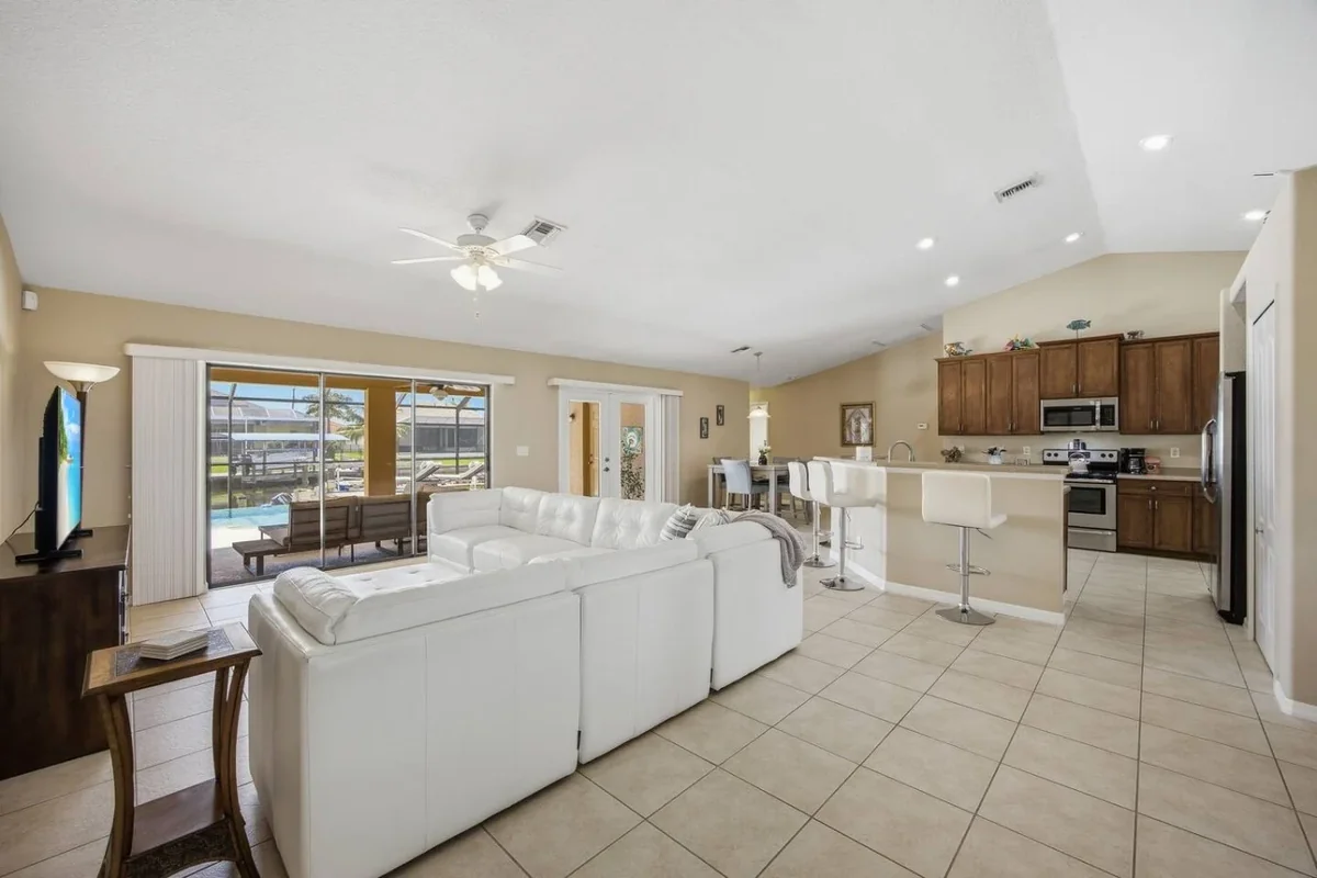 Open living room and kitchen in a Cape Coral canal home with white seating and patio doors