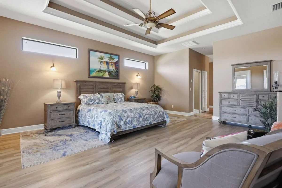 Cape Coral villa bedroom with a ceiling fan, upholstered bed and dresser